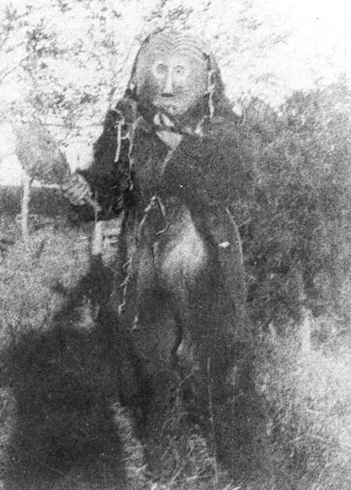 Associated image for entry 'the Mësinkw impersonator, a man dressed in bear hide clothes with the carved wooden mask.'